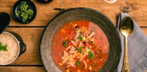 Top view of a delicious Mexican soup with sides of rice and herbs, perfect for a cozy meal.
